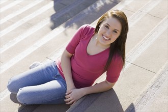 Teenage girl sitting on steps. Photographe : PT Images
