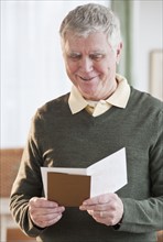 Senior man reading greeting card.