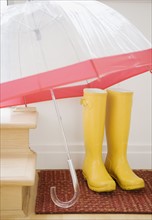Rain boots and umbrella drying indoors. Photographe : Jamie Grill