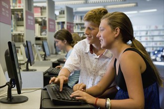 Teenagers using computer in library. Photographe : mark edward atkinson