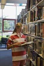 Girl reading book in library. Photographe : mark edward atkinson