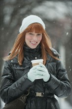 Woman holding coffee in snow.