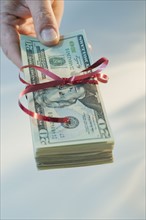 Man holding stack of money wrapped in ribbon.