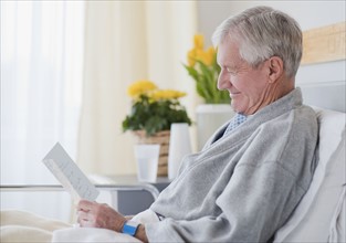 Senior man reading get well card in hospital.