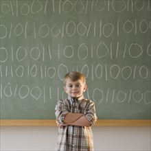 Boy writing binary code on blackboard.