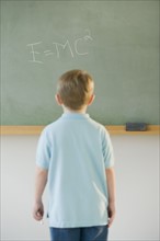 Boy writing formula on blackboard.