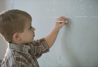 Boy doing math on blackboard.