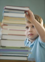 Boy taking book from stack.