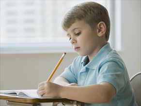 Boy writing in classroom.