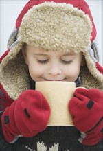 Boy in warm hat drinking hot chocolate.