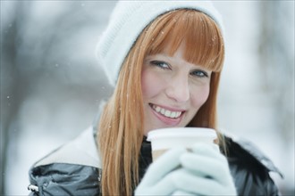 Woman drinking coffee in snow.