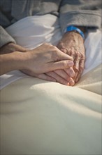 Nurse holding elderly man’s hand.
