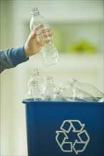 Boy filling recycling bin with water bottles. Photographe : Daniel Grill