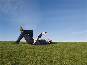Businessman laying in grass.