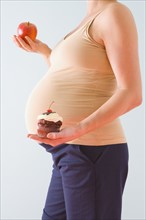 Pregnant woman holding healthy and unhealthy snacks. Photographe : Jennifer L. Boggs
