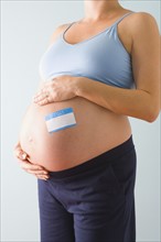 Pregnant woman with blue name tag on belly. Photographe : Jennifer L. Boggs
