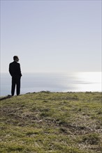 Businessman looking toward ocean. Photographe : PT Images