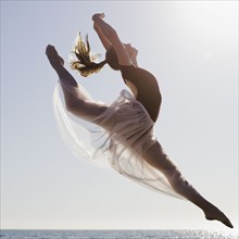 Dancer leaping on beach. Photographe : PT Images