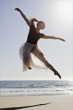 Dancer leaping on beach. Photographe : PT Images