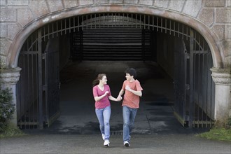 Young couple running through tunnel. Photographe : PT Images