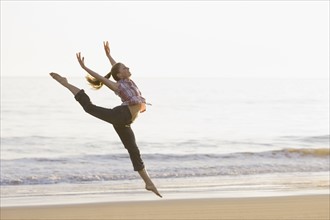 Woman dancing on beach. Photographe : PT Images