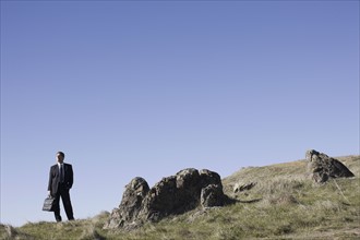 Businessman standing on remote hill. Photographe : PT Images