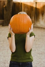 Girl holding pumpkin over face. Photographe : Sarah M. Golonka