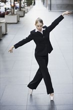 Businesswoman dancing in urban setting. Photographe : PT Images
