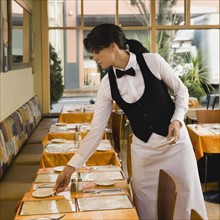 Waitress setting restaurant tables.