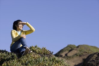 Teenage girl sitting on hill. Photographe : PT Images