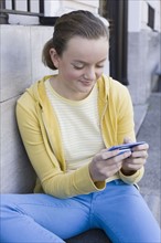 Girl text messaging on steps. Photographe : PT Images