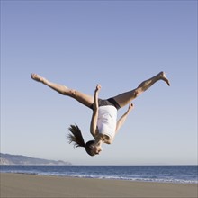 Woman jumping on beach. Photographe : PT Images