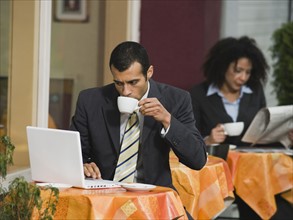 Businessman looking at laptop at outdoor cafe.