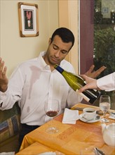 Waiter spilling wine on customer.