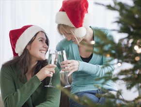 Women toasting with champagne at Christmas. Photographe : Jamie Grill