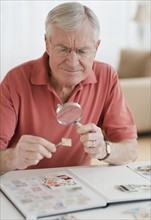 Senior man looking at stamp collection.