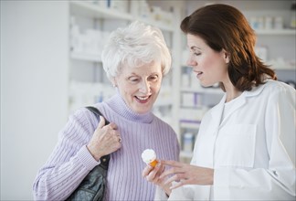 Pharmacist helping senior woman with prescription.