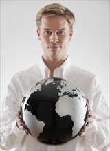 Businessman holding black and white globe.