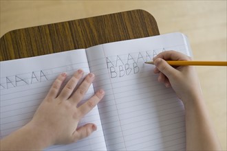Boy writing letters in classroom.