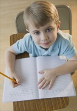 Boy writing letters in classroom.