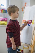 Boy painting on easel.