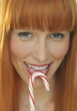Woman licking candy cane.
