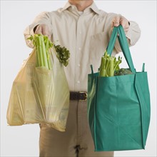 Man holding reusable grocery bags.