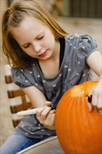 Girl drawing on pumpkin