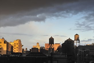 Cityscape with water towers at sunset, New York City, New York, USA.
