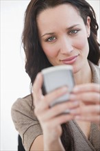 Woman using palmtop, smiling.