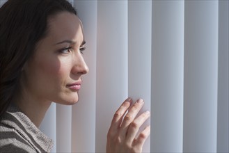 Woman looking through blinds.