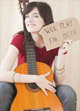 Portrait of young woman with guitar, playing for beer. Photographe : Jamie Grill