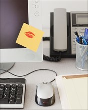 Adhesive note with lipstick kiss on computer monitor. Photographe : Jamie Grill