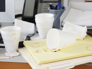 Messy office desk with empty disposable cups. Photographe : Jamie Grill